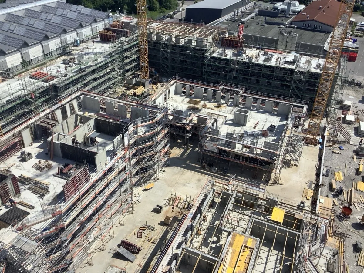 Luftbild einer Großbaustelle mit mehreren Rohbauten und Kränen